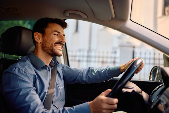 Happy businessman driving car through city.