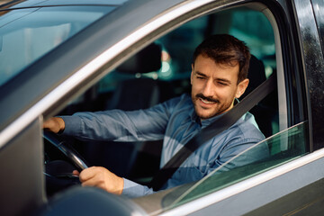 Happy man parking car in reverse while looking at side view mirror.