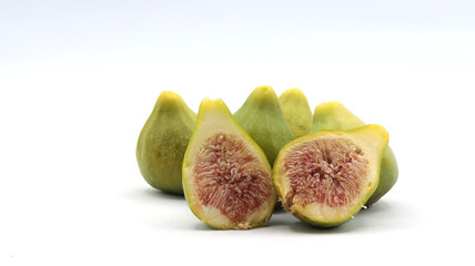 close-up of a group of green figs, one of which is cut in half, on a white background