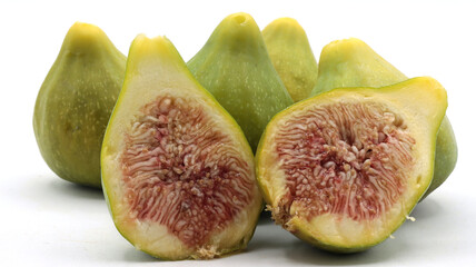 close-up of a group of green figs, one of which is cut in half, on a white background