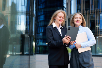 Professional women collaborating in a modern urban setting during a sunny afternoon