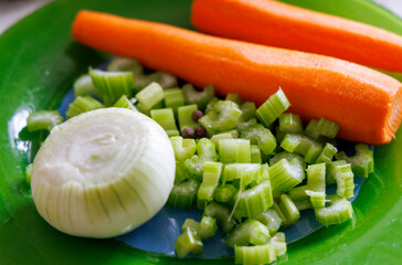 
fresh, chopped vegetables on a green surface: a large carrot, chopped celery stalks and half an...