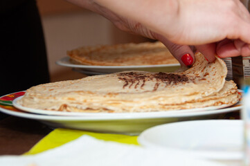 Women's hands put the stuffing and wrap pancakes in a tube