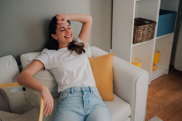 Young woman relaxing on sofa after finishing laundry at home