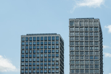 Fototapeta premium Two buildings with modern apartments at city. Architecture skyscrapers against blue cloudy sky.