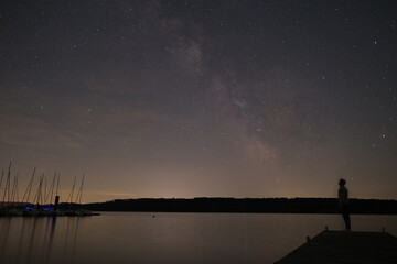 Silhouette on Dock Under Starry Sky – Milky Way Reflections at Night