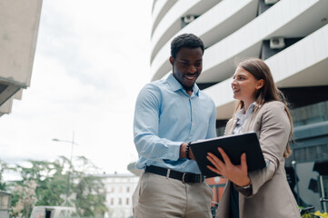 Smiling business colleagues using tablet in urban setting
