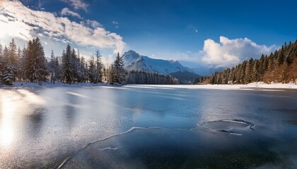in the winter by the lakeside tranquility and peace prevail the lake is covered with a thin layer of ice reflecting the soft light from the sun that filters through the sparse clouds casting a sil