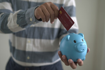 Young asian man holding credit card and piggy bank for shopping and paying online, ordering...