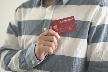 Young asian man holding credit card and piggy bank for shopping and paying online, ordering...