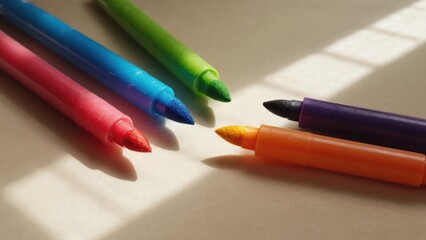 Colorful marker pens arranged in star shape on sunlit surface