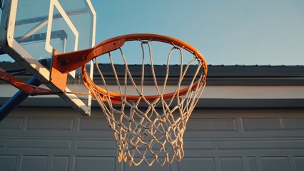 Basketball hoop against blue sky at suburban home