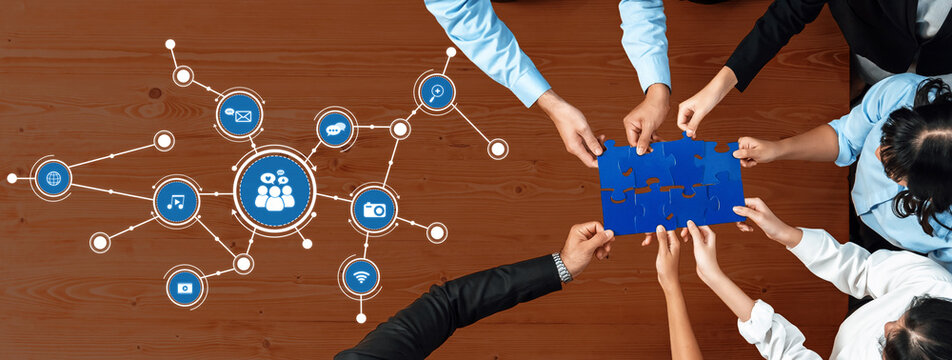 A dynamic team engages in collaborative problem-solving using puzzle pieces and technology icons on a wooden table, emphasizing communication and innovative thinking. Amity