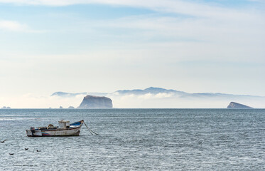 A tranquil scene with a fishing boat floating in the calm waters of Pacific Ocean at Paracas National Reserve, Peru.