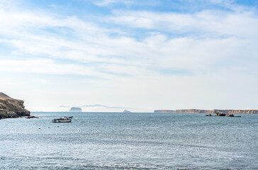 A tranquil scene with a fishing boat floating in the calm waters of Pacific Ocean at Paracas National Reserve, Peru.
