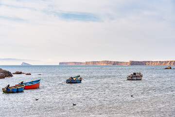 A tranquil scene with a fishing boats floating in the calm waters of Pacific Ocean at Paracas National Reserve, Peru.