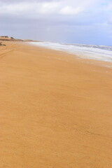 A big bright yellow sand dune on the background of bright cloudy sky. Something like a hieroglyph...