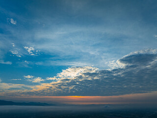 A breathtaking sunrise illuminates a small village nestled among lush green fields and karst...