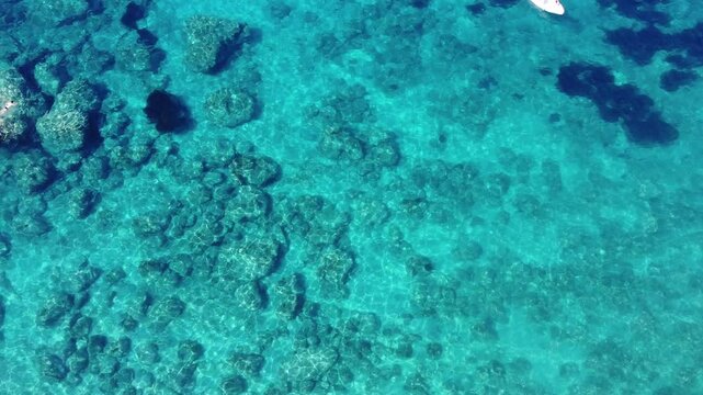 4K aerial top-down view of turquoise water in Corfu, Greece on a sunny day