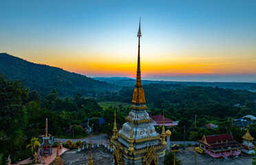 Aerial view of Mae Klang Waterfall Temple in Chiang Mai with the sunrise casting warm hues in calm...