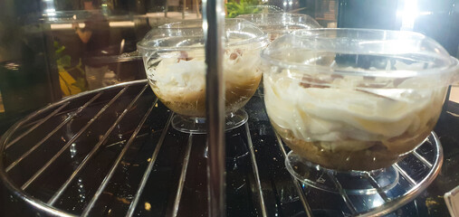 Sweet fruit and cream dessert on a glass spinning display case in a cafe. Cold dessert, ice cream.