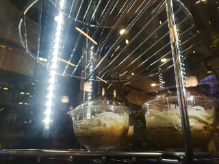 Sweet fruit and cream dessert on a glass spinning display case in a cafe. Cold dessert, ice cream.
