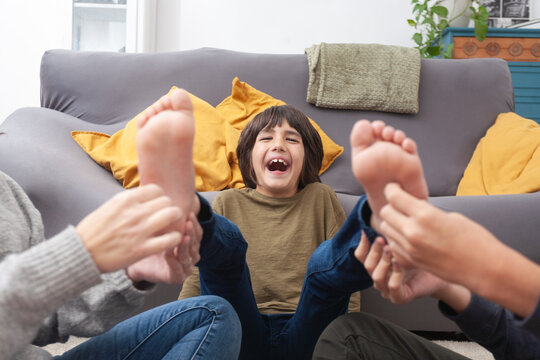 Laughing child gets tickled by family at home