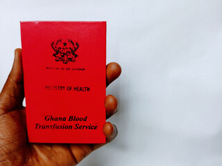Holding Ghana blood donor certificate on white background. Red blood donor book to record donor's...