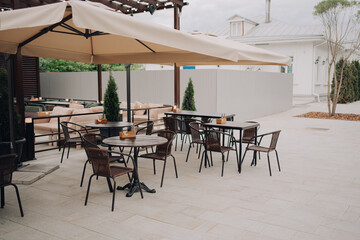 Elegant outdoor seating area featuring tables, chairs, and umbrellas, creating a cozy modern cafe...