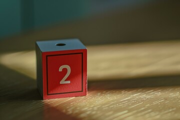 Red wooden block with number two standing on wooden table