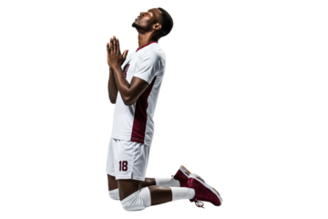 Male volleyball player in a white and maroon uniform kneeling and looking up with hands in prayer