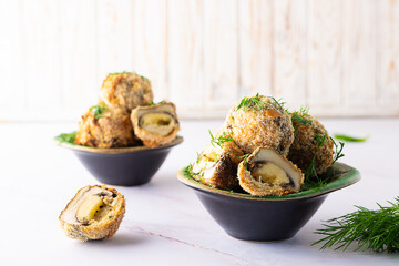 Crispy mushroom balls with cheese and spices baked in bread crumbs in dark ceramic bowl on on light kitchen table close up. Healthy homemade snack.