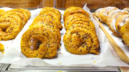 Freshly baked spiral pastries decorated with flax seeds on display at a bakery. Perfect for breakfast, brunch or a holiday treat.