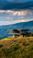 Modern glass house overlooking lush hillside and mountain scenery under dramatic sky
