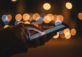 Using smartphone at night bokeh background mobile technology social media apps communication device connection