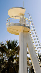 White lifeguard tower stands near palm trees. Image suitable for beach safety, tourism, or coastal...
