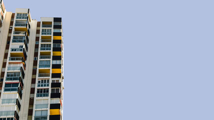 Tall residential apartments with geometric, colorful balconies under clear blue sky, copy space for...