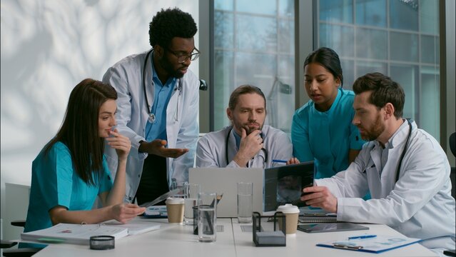 Stressed nervous group of multiethnic diverse doctors men women interns medical students quarreling coworkers confused about diagnosis brainstorming arguing conflict conversation meeting room hospital