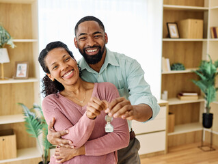 Portrait of a young couple unpacking, holding apartment keys, moving in and relocation to a new...