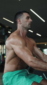 A young brutal male athlete is a bodybuilder with a perfect abs, exercising in the gym. Concept - strength, bodybuilding, styrodes, weightlifting, diet, muscles, sports nutrition, personal trainer