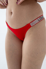 Red women's briefs on the model. young woman's body in red thong panties