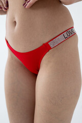 Red women's briefs on the model. young woman's body in red thong panties