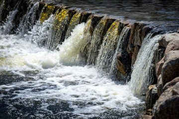 Cascading water over rocky barrier in a serene river scene