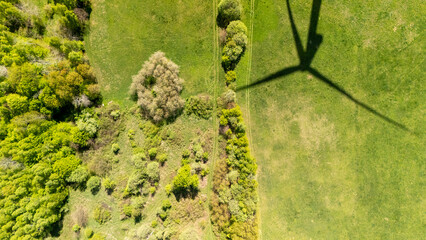 Aerial view of a green landscape showing diverse vegetation with a wind turbine shadow casting over...