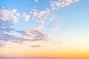 sky with wispy cirrus clouds illuminated by the setting sun in soft orange tones. Celestial landscape