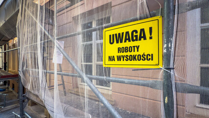 Rusztowanie metalowe, roboty na wysokości, remont elewacji, budynku, tablice ostrzegawcze, siatka ochronna.