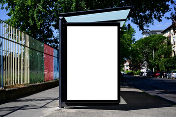 bus shelter at a busstop. blank billboard ad display. empty white lightbox sign. ad space. city transit station. glass structure. urban street setting. outdoor advertising concept.