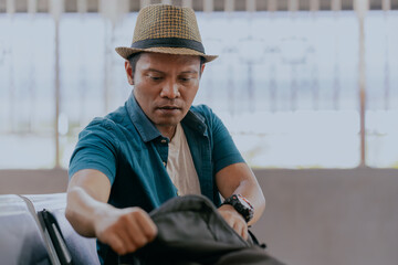 Preparing to travel. Asian man checks his backpack while sitting at the station waiting for the...