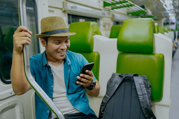 Happy asian man watch the video with his smartphone on the MRT or train. Travel lifestyle concept.
