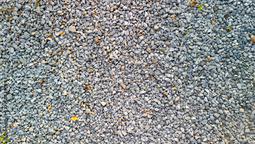 Poster close-up view of a gravel surface, showcasing various sizes of gray stones intermixed with small bit